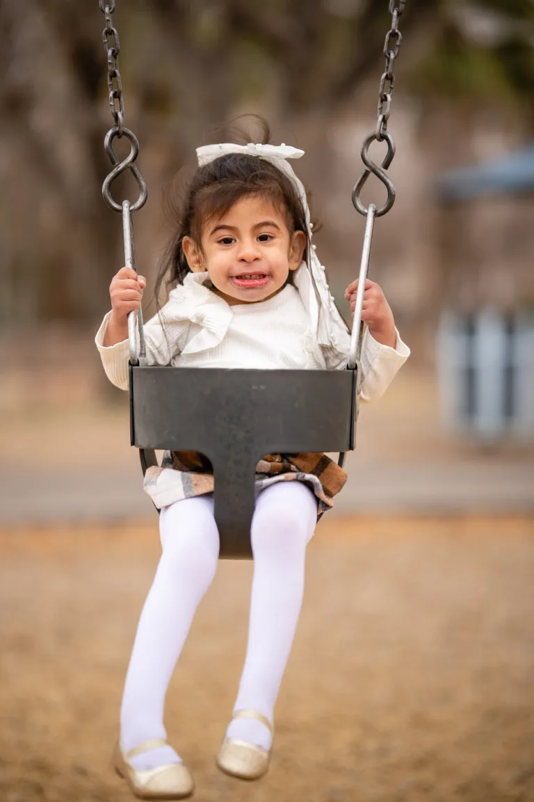 Niña sentada en un columpio y sosteniendo las cadenas
