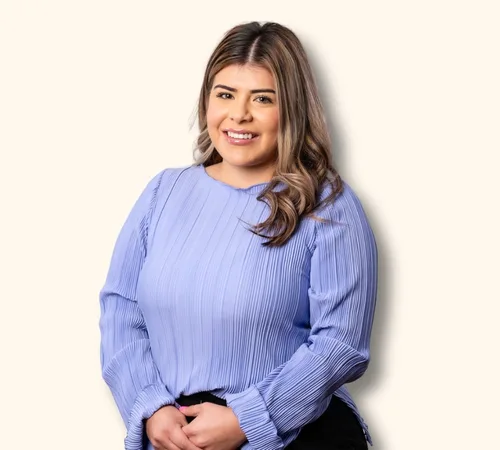 Retrato de Cinthia Herrera con una blusa azul claro sobre un fondo liso