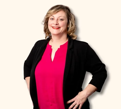 Retrato de Erin O'Donnell con un top rosa y un cárdigan negro sobre un fondo claro