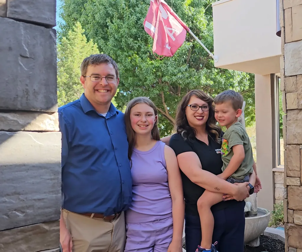 Lindy Matthews and Family smiling at the camera outside the Aprendamos Office.