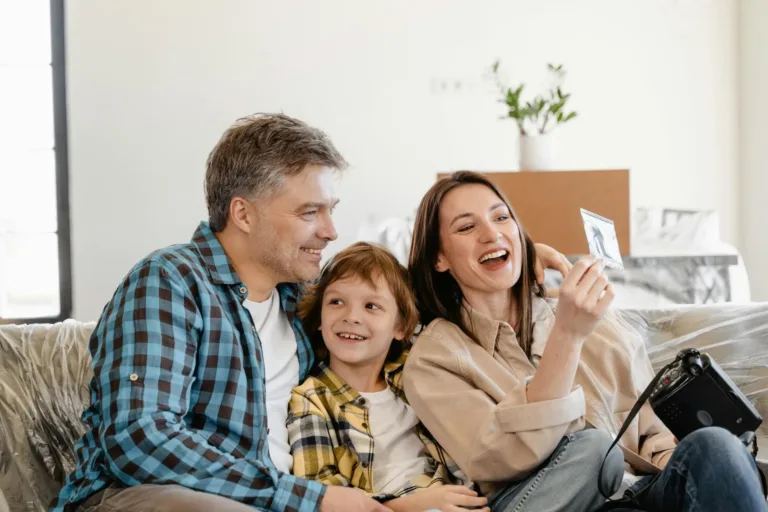 A family sitting together on a couch, smiling and interacting, representing supportive counseling.