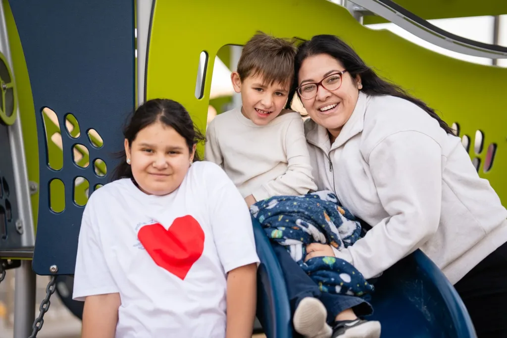 A parent and her children smile at a colorful therapy center in the Mariposa Autism Service Center.
