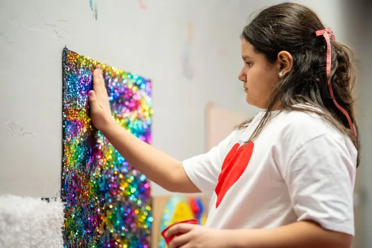 Niño tocando un panel sensorial de pared colorido durante terapia de apoyo al procesamiento sensorial.