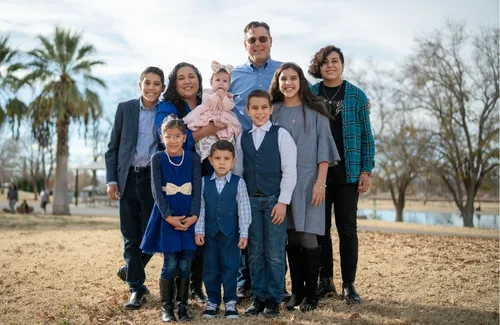 Una familia de ocho personas posando juntos al aire libre en un parque