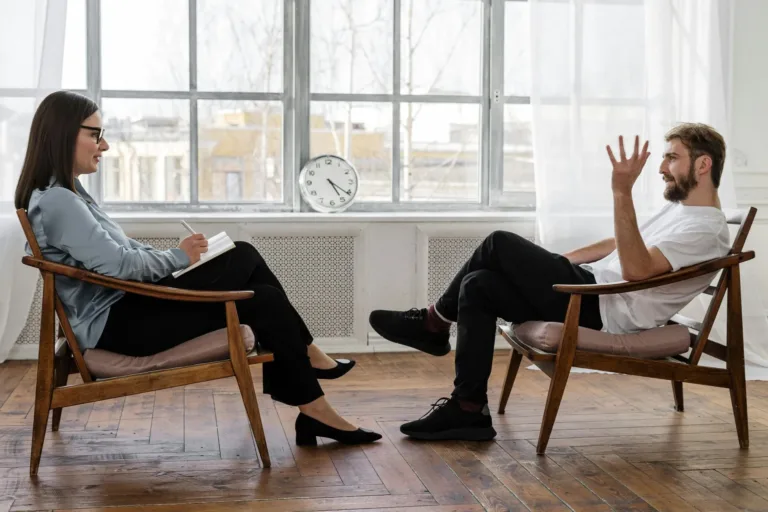 A therapist sitting next to a man during anger management.