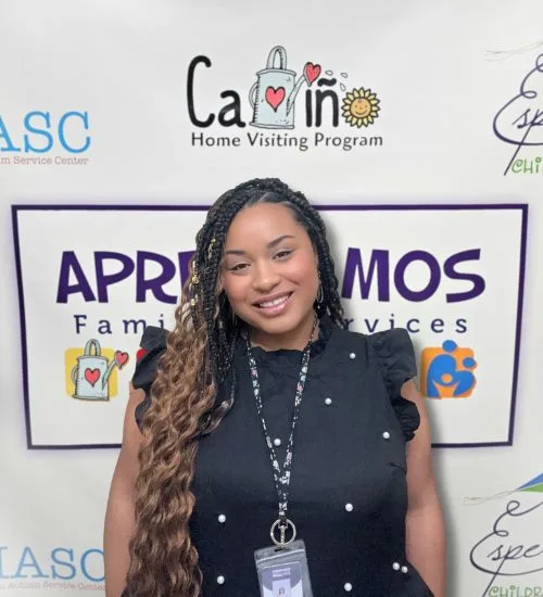 Woman with long braids smiles in front of a sign for family services.
