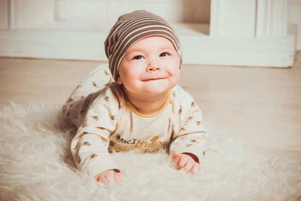 Smiling baby sitting on a rug, representing free early intervention services available for families.