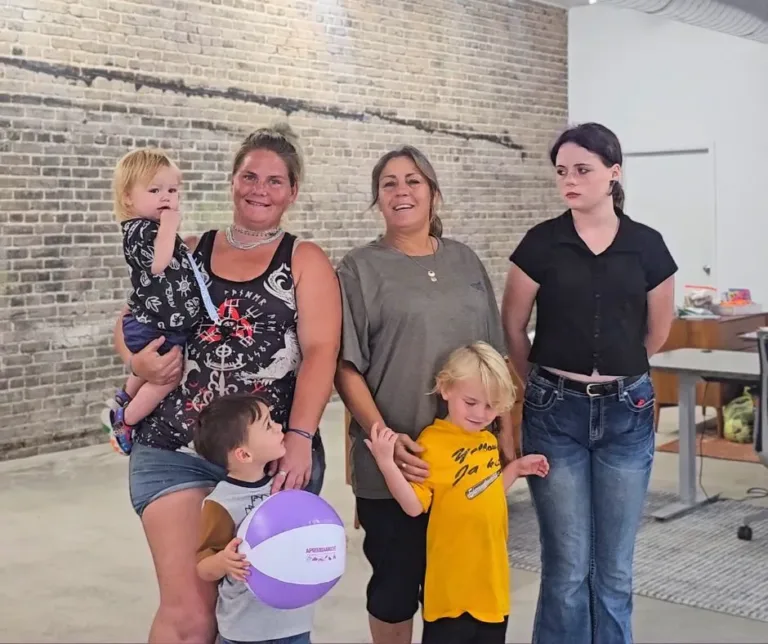 Gail and her family smiling at the camera at the Aprendamos T or C Office.