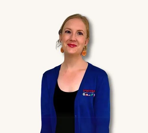 Portrait of Halley Ross wearing a blue cardigan and orange earrings against a white background