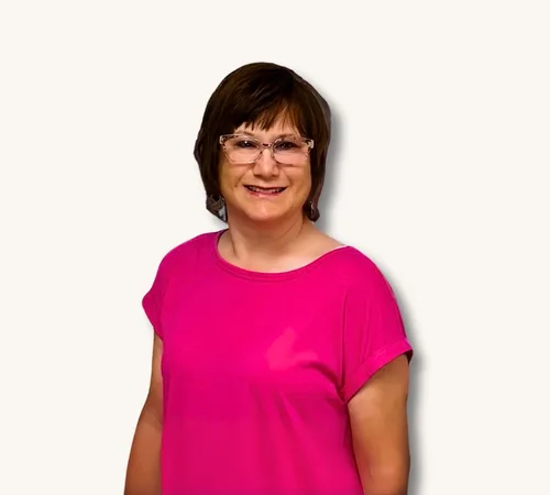 Portrait of Jennifer McAfee wearing glasses and a bright pink shirt