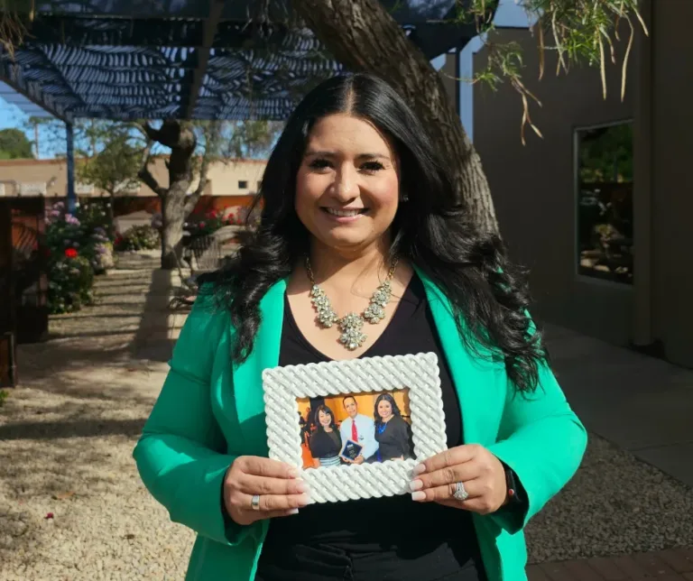 Krystal Chavarria-Gonzalez is holding a picture frame of her story at Aprendamos