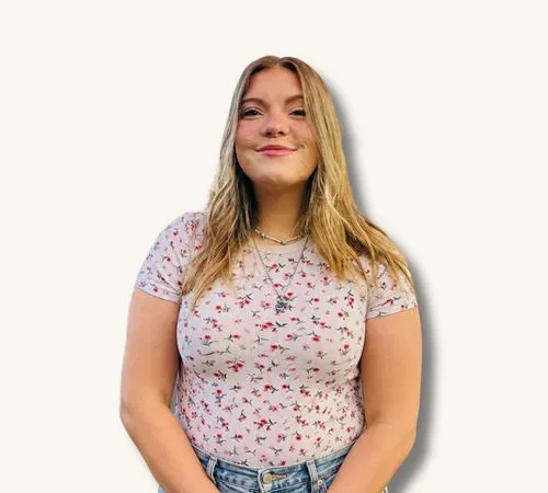 Leeann Muncy standing against a plain white background, wearing a floral shirt and jeans