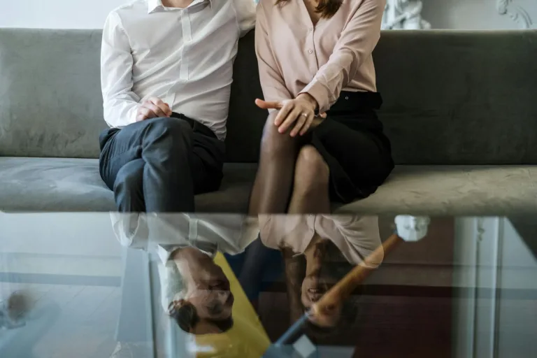 A couple sitting side by side on a couch during a counseling session.