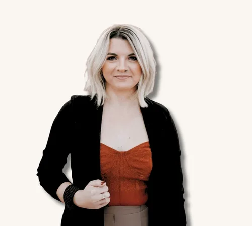 Portrait of Nicole Rivera-Brastad with blonde hair wearing a black jacket and rust-colored top
