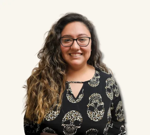 Smiling Priscila Wade with glasses and long curly hair wearing a black skull-patterned top
