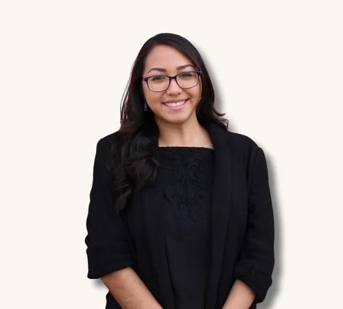 Portrait of Stephanie Gonzalez Martinez wearing glasses and a black blazer against a light background