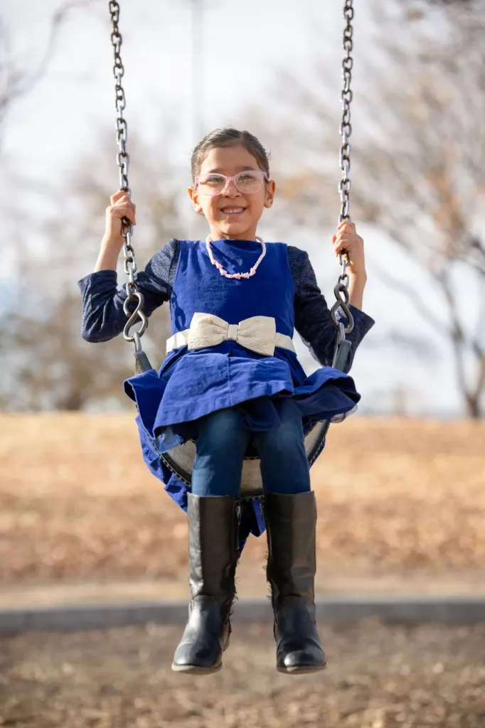 A child playing on swing smiling at the camera.