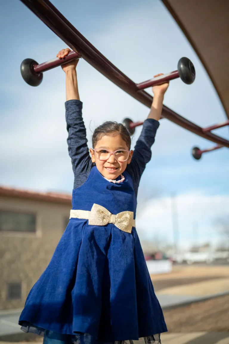 Una niña sonriendo y jugando en equipo al aire libre, representando terapia flexible y de apoyo.