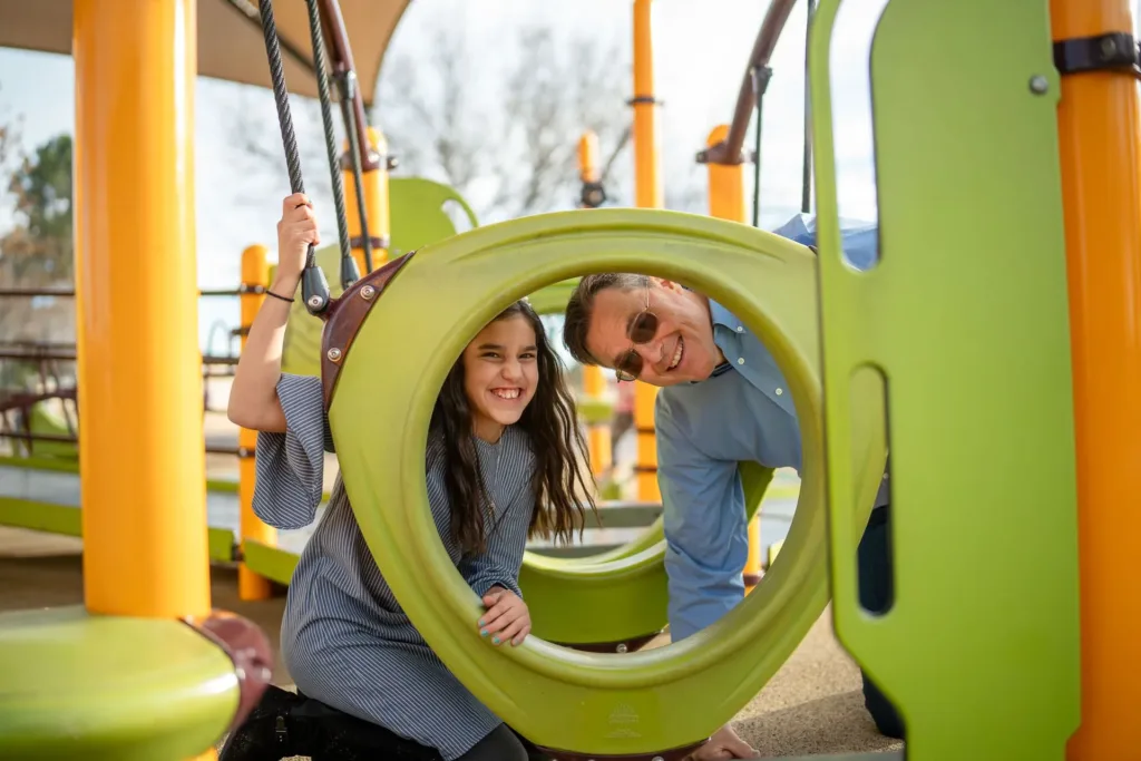 Una niña en el parque infantil con su padre.