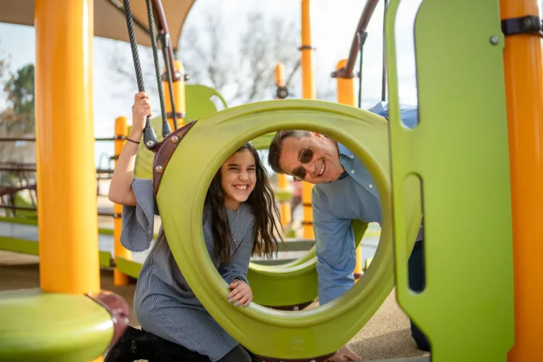 Una niña en el parque infantil con su padre.