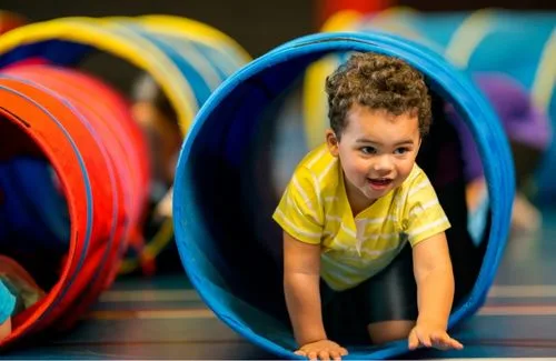 Toddler crawling through a blue play tunnel