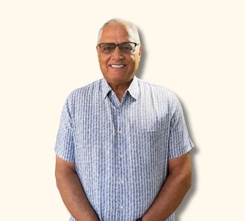 Leonard Ochart, usando gafas y una camisa azul a cuadros de manga corta, está parado contra un fondo beige claro.