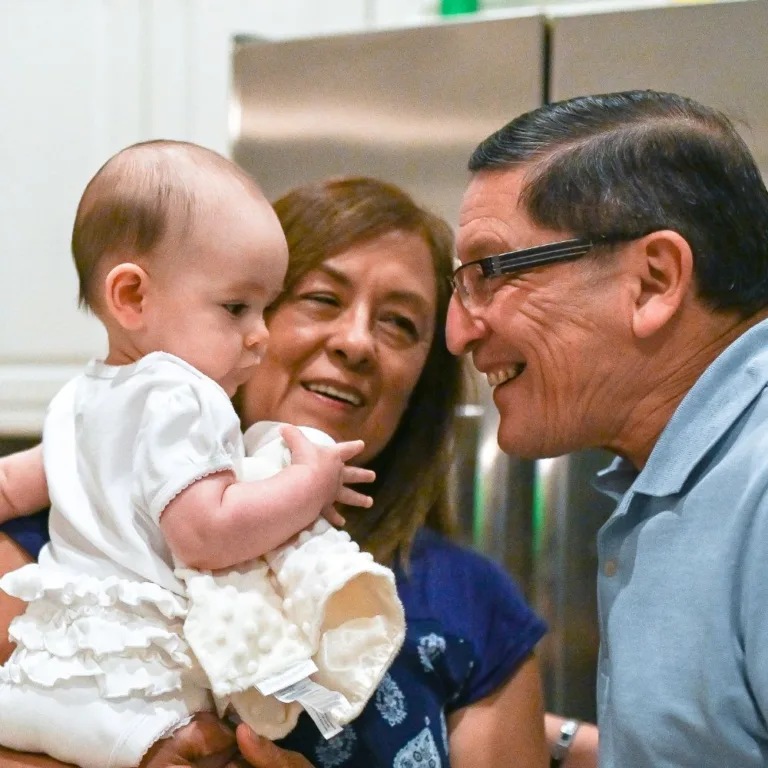An older couple smiles at a baby being held in front of them