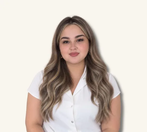 Mujer con pelo largo y ondulado de color marrón, que lleva una blusa blanca